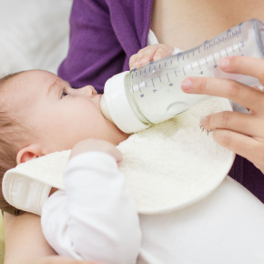 Mother feeding baby with milk from a bottle.