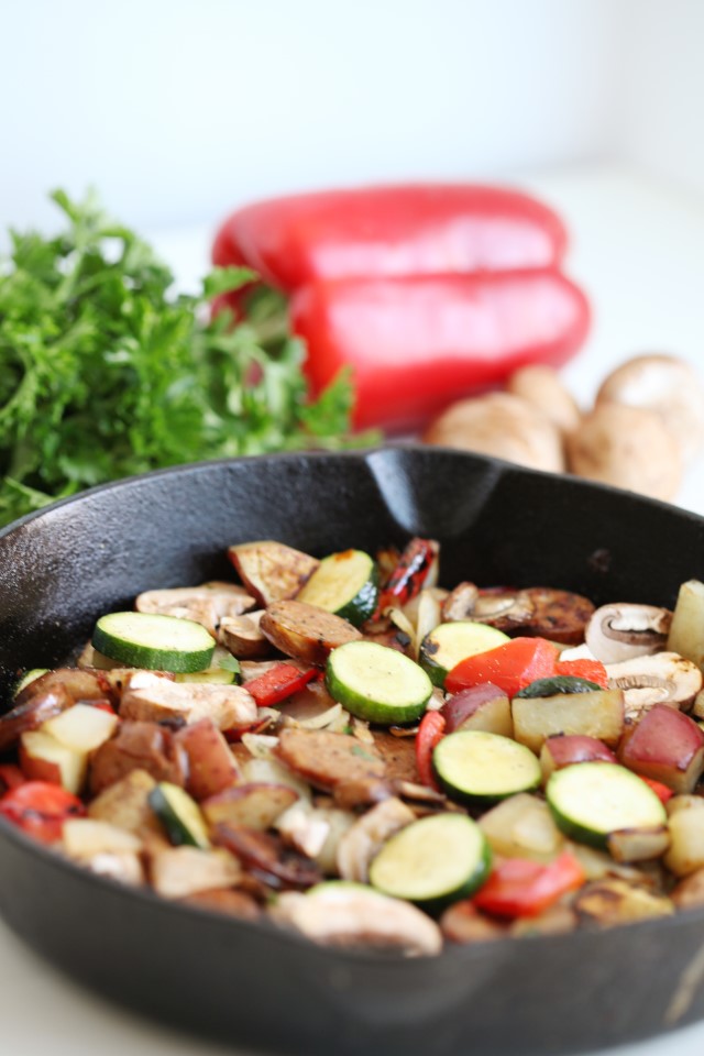 a cast iron skillet with vegetables and sausage